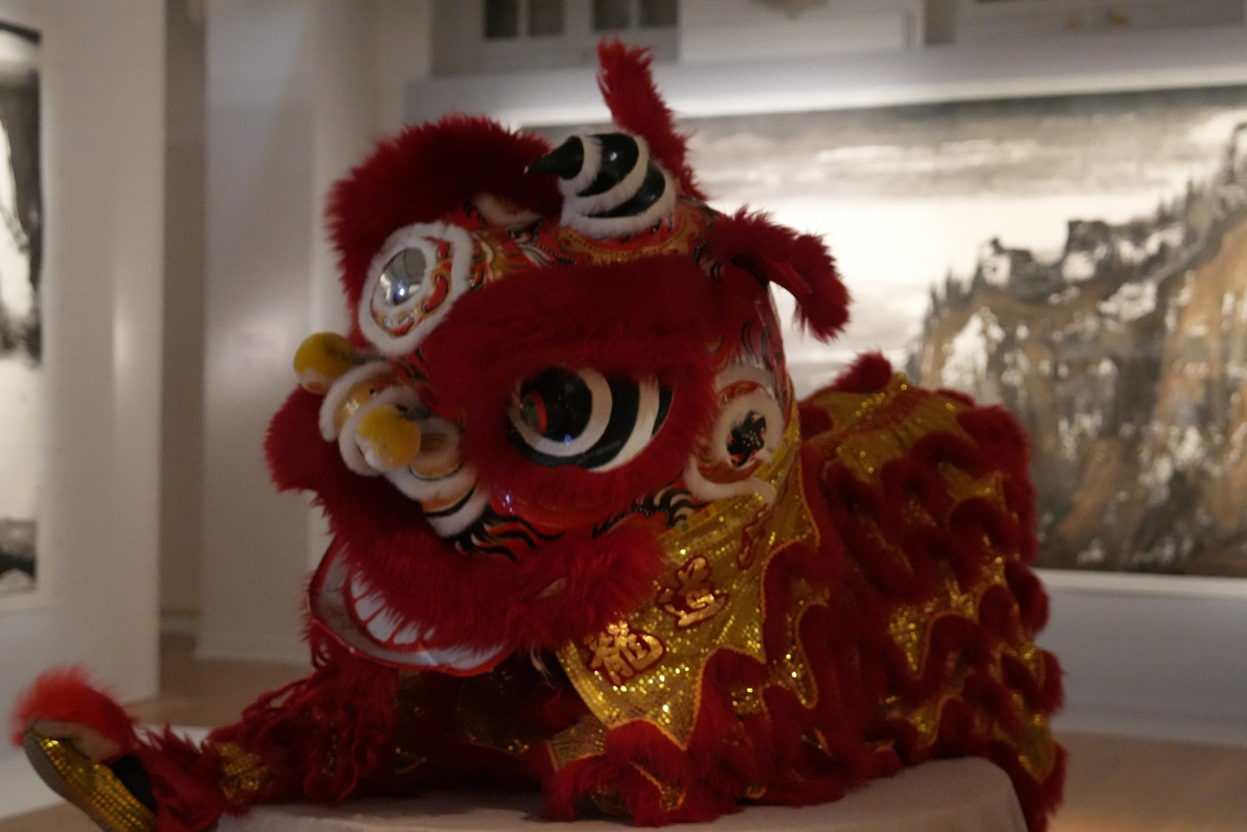 Un costume de lion chinois dans une des salles du musée en arrière plan une peinture