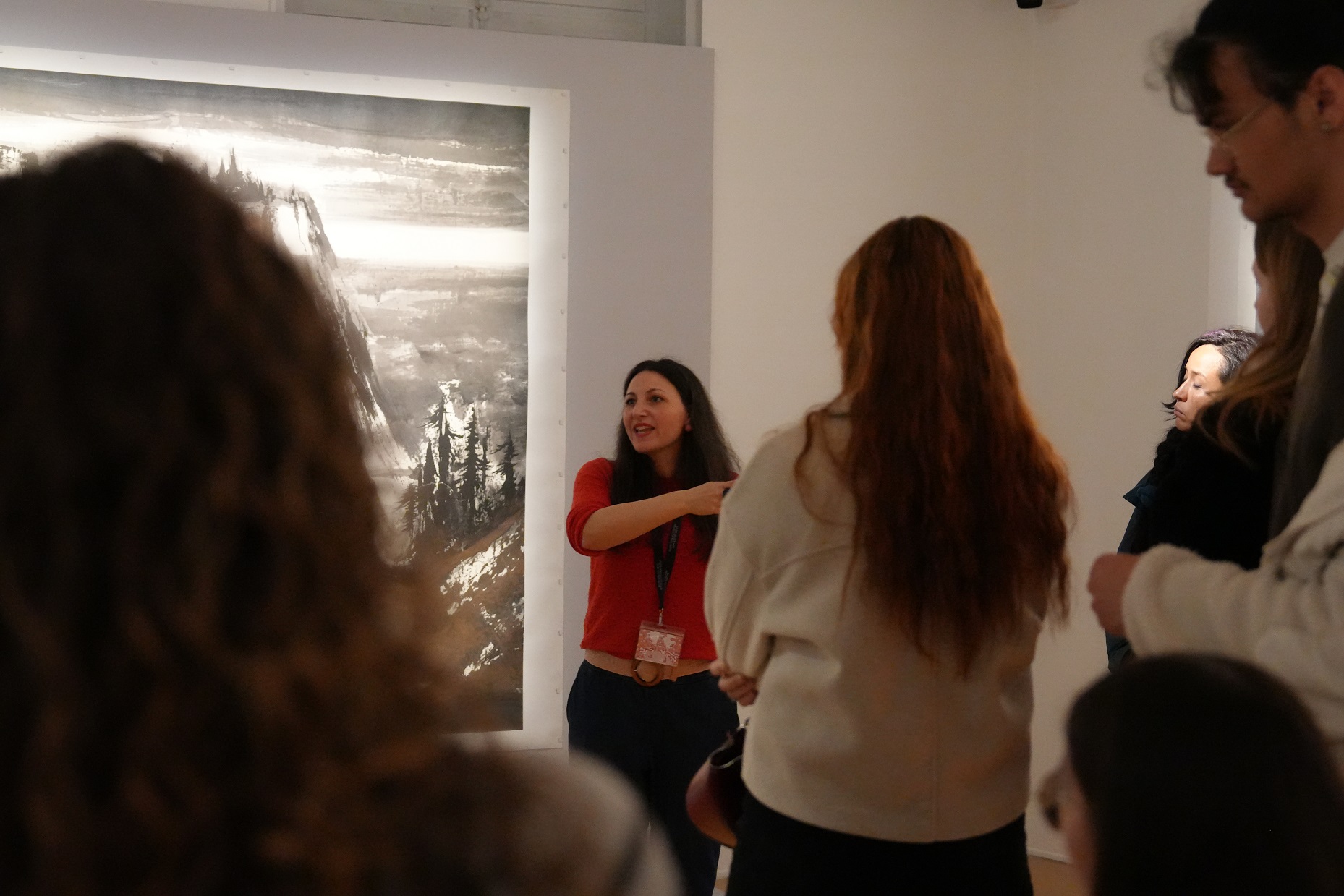 Une médiatrice éxplique face à du public et dos à une peinture